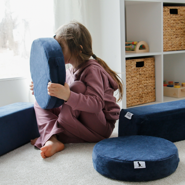 Child playing with cushion pieces from a modular foam play couch for kids—high-density, safe, and soft Canadian floor couch ideal for creative play.