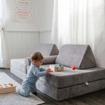 Baby playing with toys on a soft grey modular foam play couch for kids—safe Canadian floor couch perfect for toddlers’ indoor playtime.