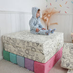 Toddler sitting on Miffy™ x Roo & You™ Joey Play Couch covered in bunny print.