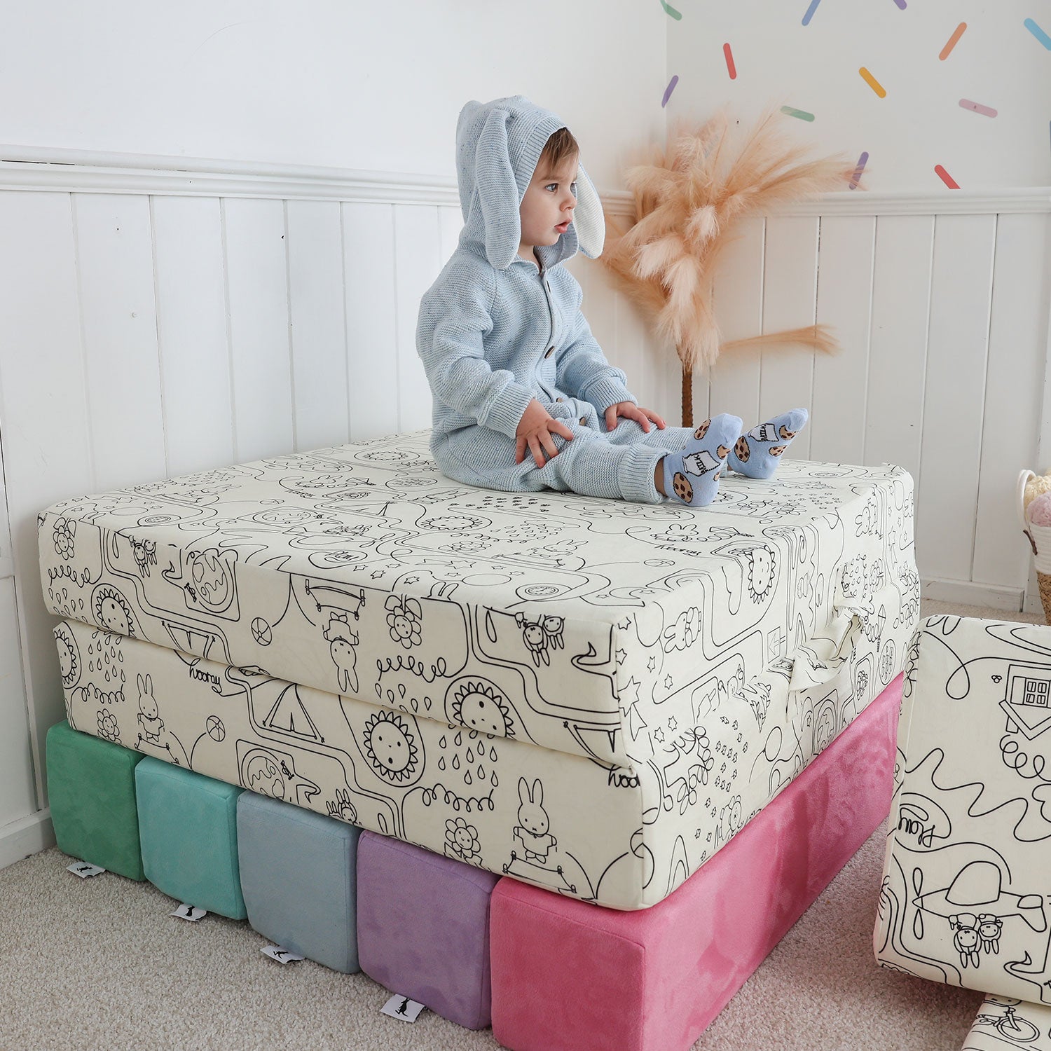 Toddler sitting on Miffy™ x Roo & You™ Joey Play Couch covered in bunny print.